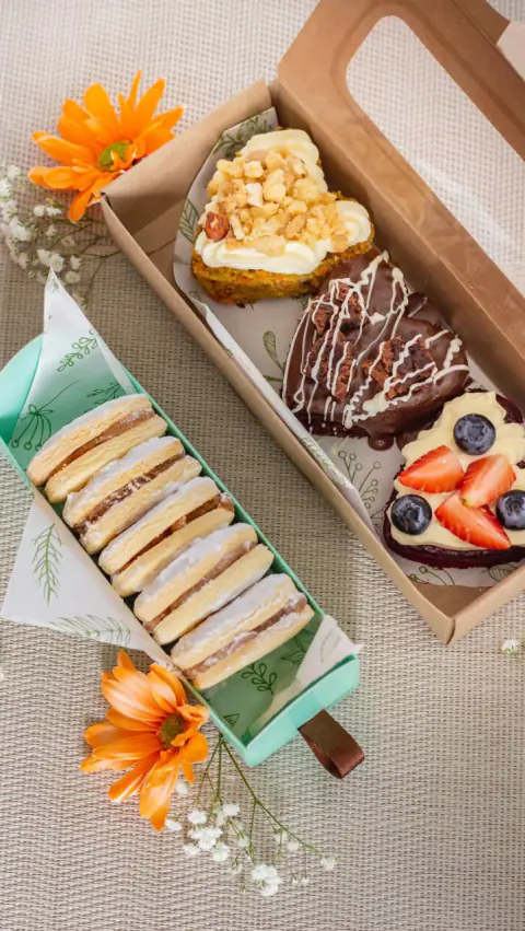 Cajas de regalo con alfajores, mini tortas y flores naranjas