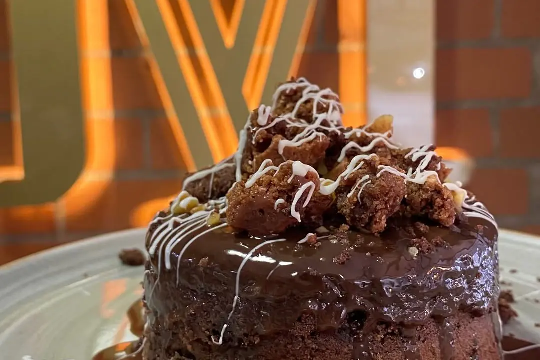 Torta de chocolate con salsa de caramelo frente a la M iluminada de La Moldería