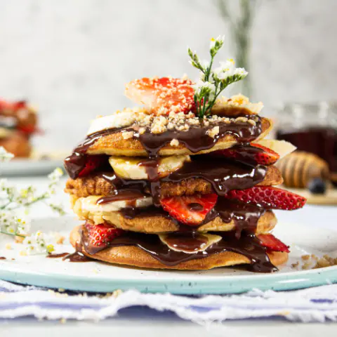 Torre de pancakes con fresas, banano y chocolate